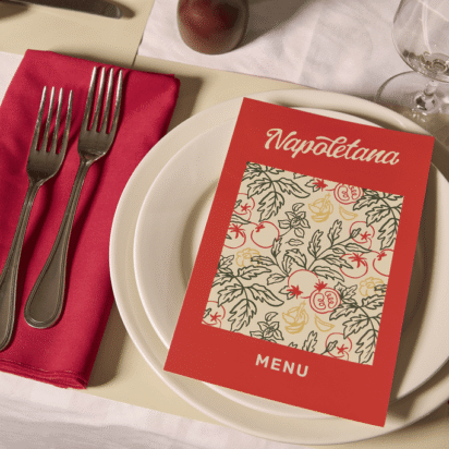 A restaurant table setting with a red menu titled “Napoletana” placed on a white plate, next to red napkin and silver cutlery.