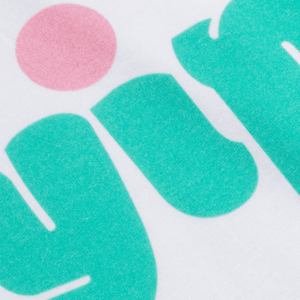 A close-up of a two-toned, mint-green and pink brand logo printed on white fabric using the Direct-to-Garment (DTG) printing method