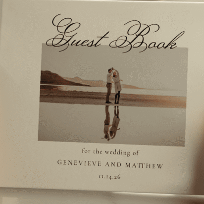 Close-up of a personalized wedding guest book held by a guest, featuring a photo of the couple and elegant script text.