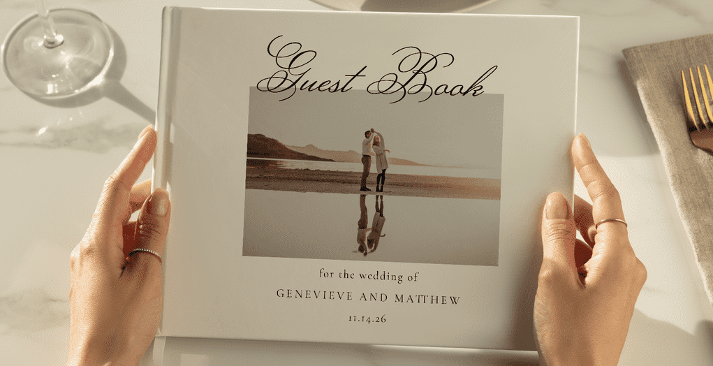 Close-up of a personalized wedding guest book held by a guest, featuring a photo of the couple and elegant script text.