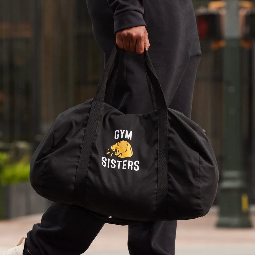 person carrying black branded gym duffel bag