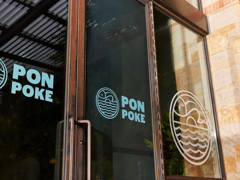 Branded adhesive window decals on a poke storefront window