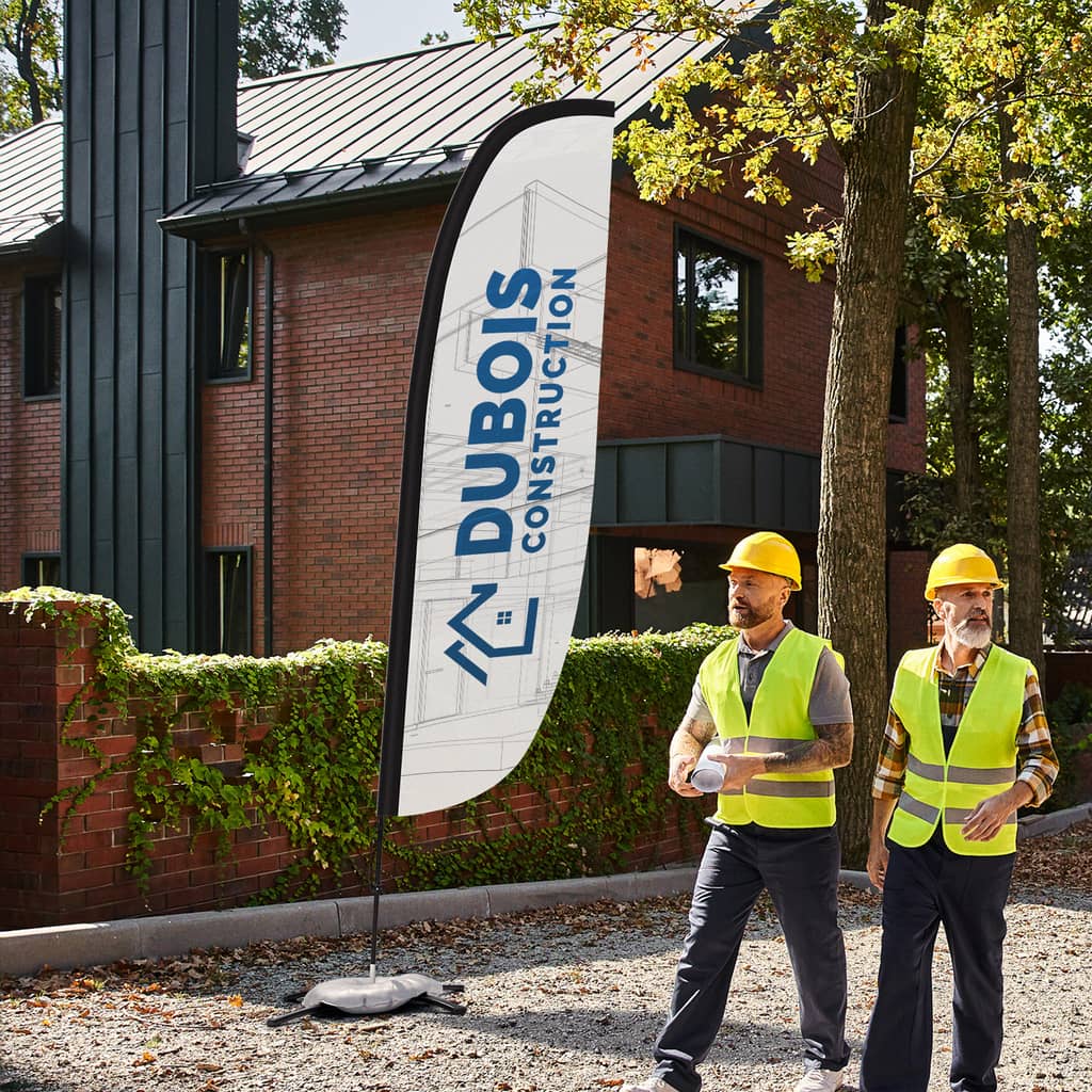 Construction company feather flag outside with construction workers walking past