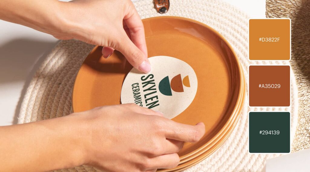 Woman places sticker featuring minimalistic ceramics logo of stacked bowls in earthy shades terra cotta, ocean blue and beige.