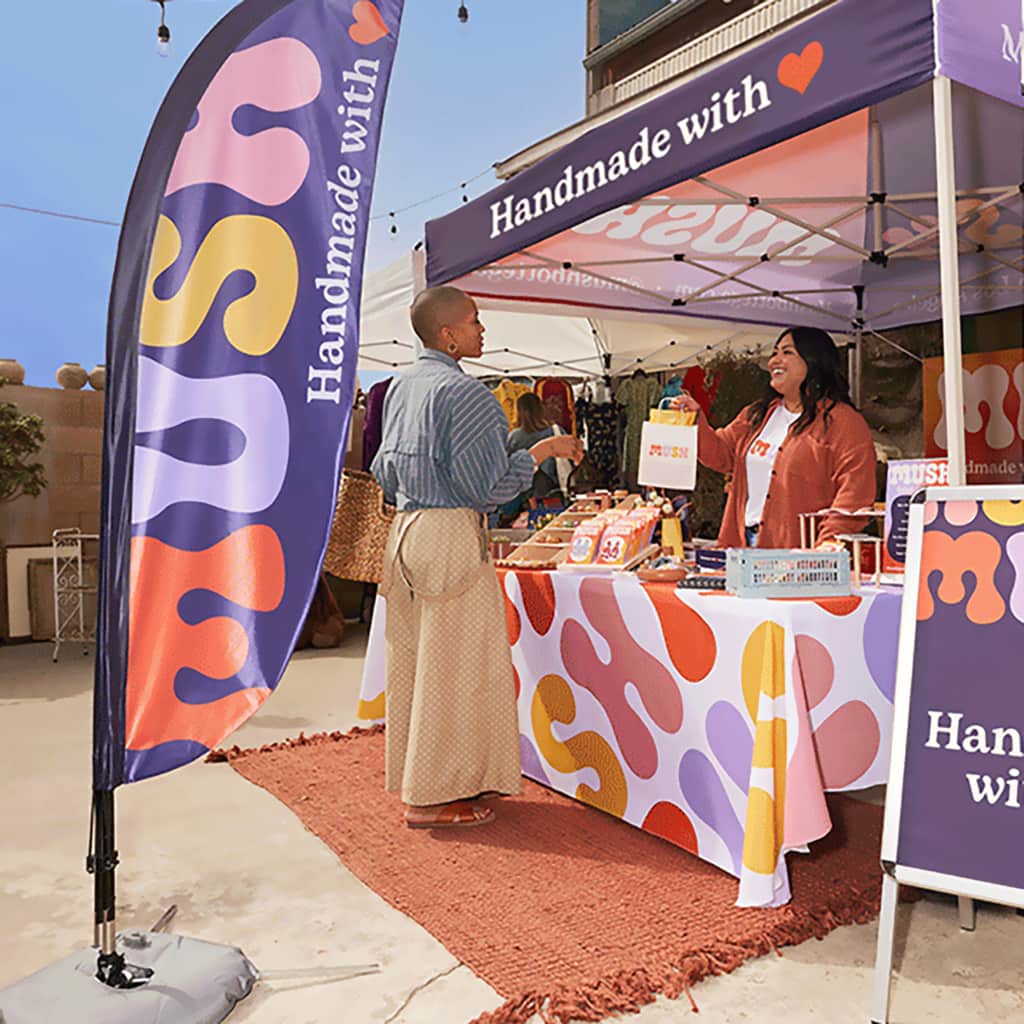 Branded feather flag in front of a trade show stall with customer being served