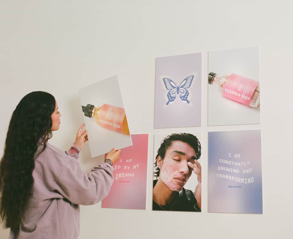 A woman placing pink and purple posters on a wall