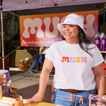 Outdoor event marketing booth at craft fair with branded apparel, signage and promotional display attracting visitors