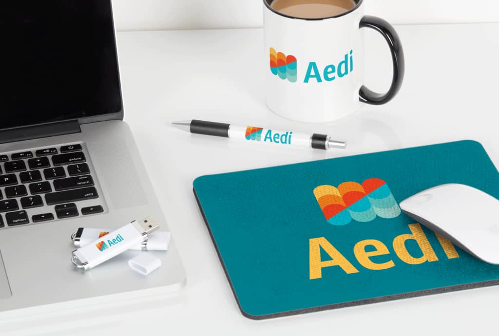 Aedi mug, pen and mousepad promotional merch in bold, vibrant colors.