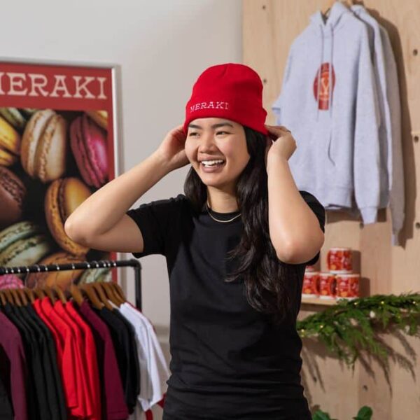 A woman wearing a branded beanie with the logo at the front of the hat