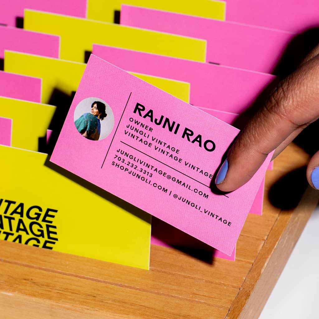 A stack of bright pink and yellow business cards for vintage store small business owner