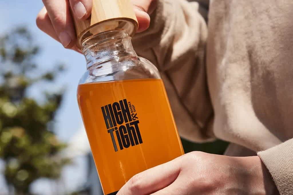 A clear High & Tight water bottle with black logo and with a picturesque background.