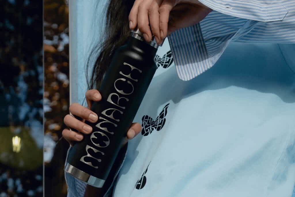 Woman opening sleek, black Monarch branded bottle