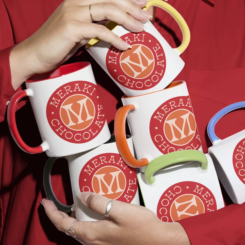 A stack of white mugs with a red logo for a chocolate brand