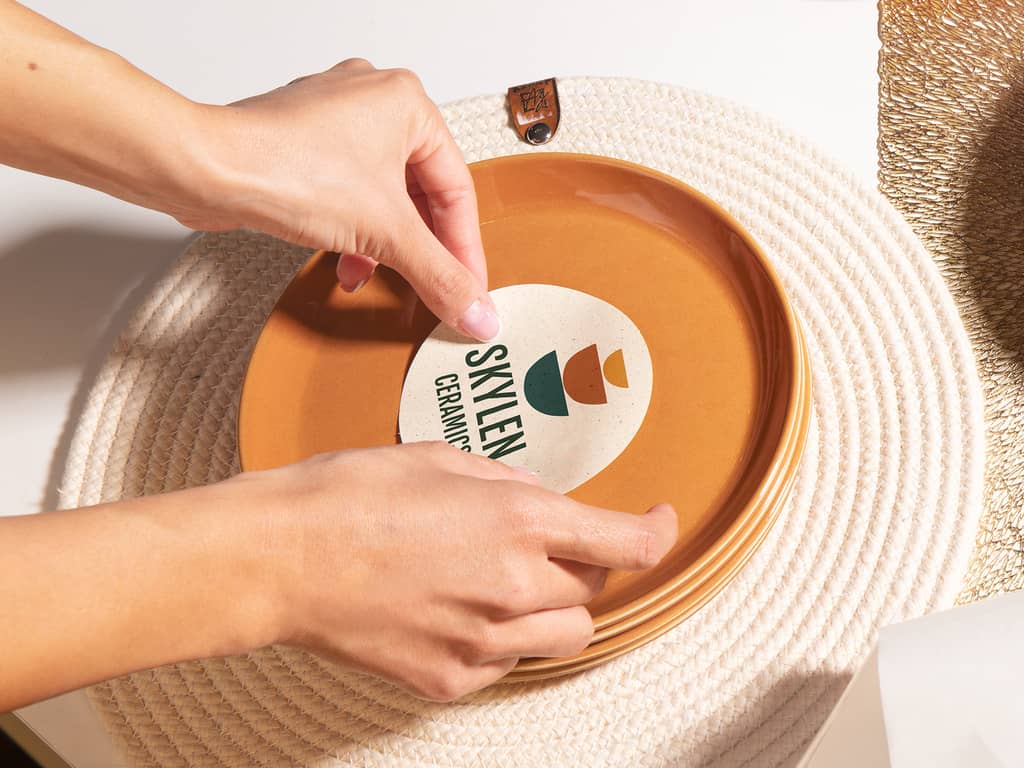 ceramics business owner placing branded sticker on a plate