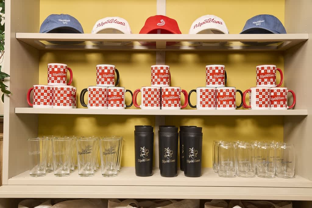 Shelves with branded mugs, water bottles, glasses and caps for an Italian restaurant