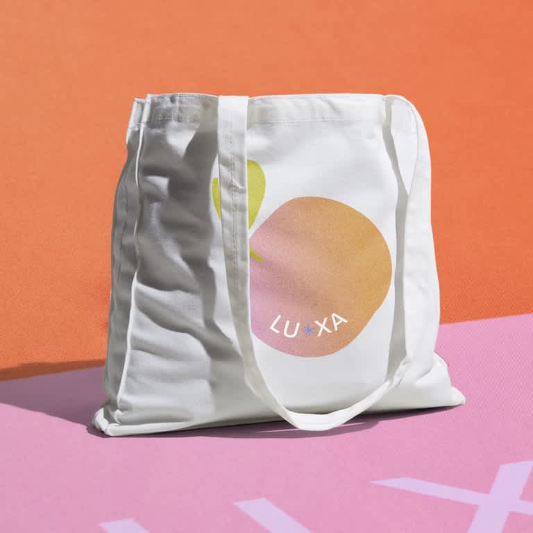 Branded white cotton tote bag with simple peach logo