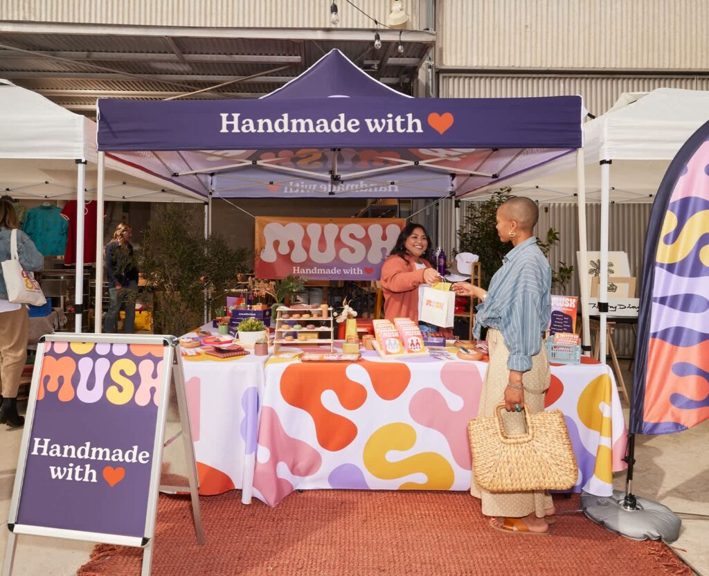 Small business event marketing booth with branded canopy, tablecloth, banner, A-frame sign and product displays