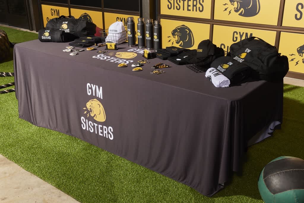 A table with a black table with a collection of branded merch for a gym brand