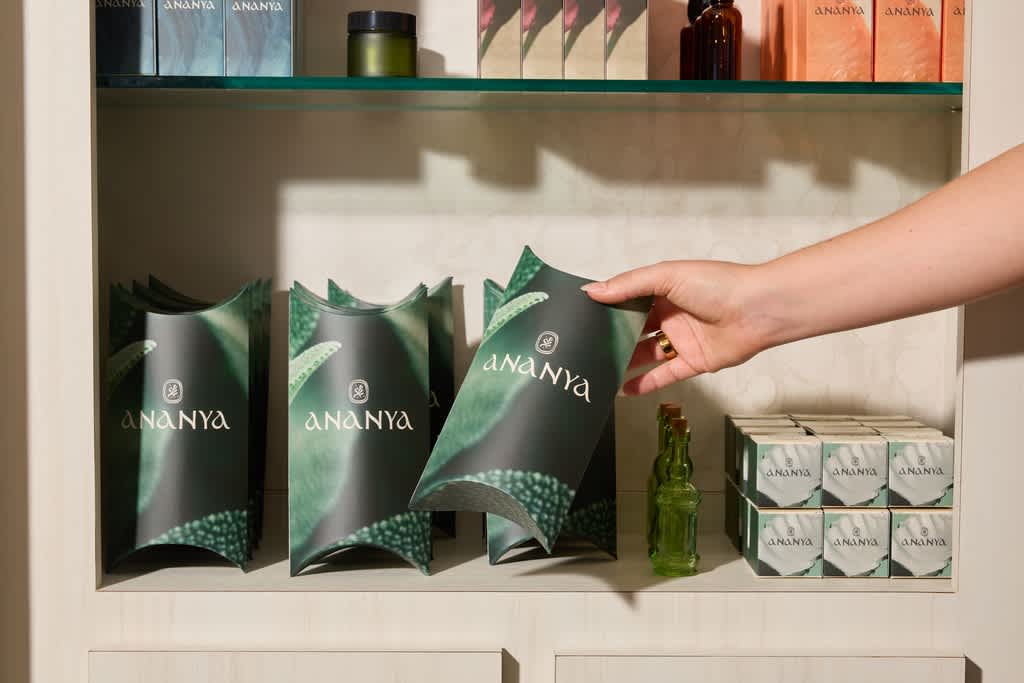 Customer reaches for beauty products in green and black box packaging on a shelf.