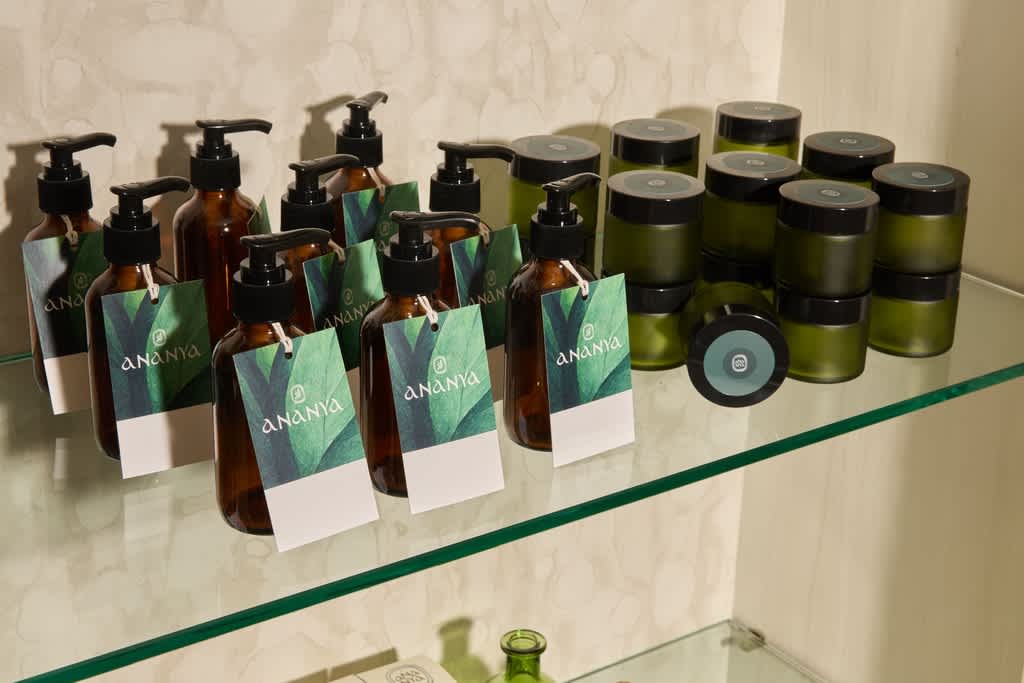 A range of branded bottles and jar packaging with green labels on a glass shelf.
