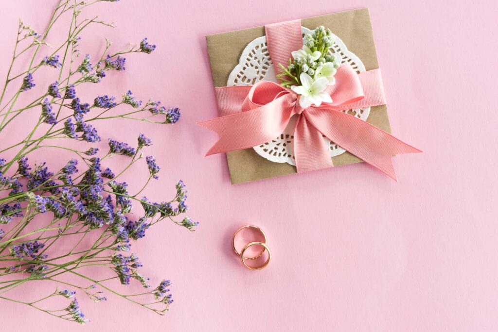 A decorated wedding card envelope with pink ribbon and flowers