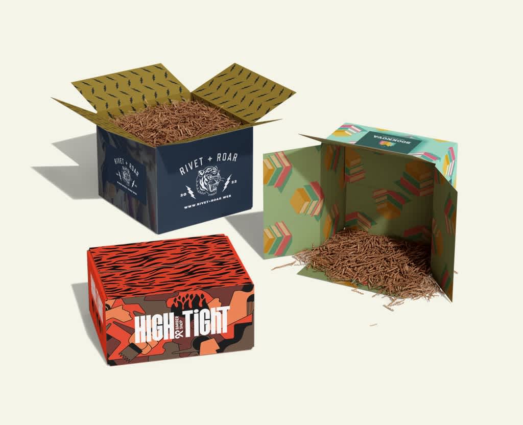 Three eco friendly cardboard box packages in different sizes, with shredded box filler.