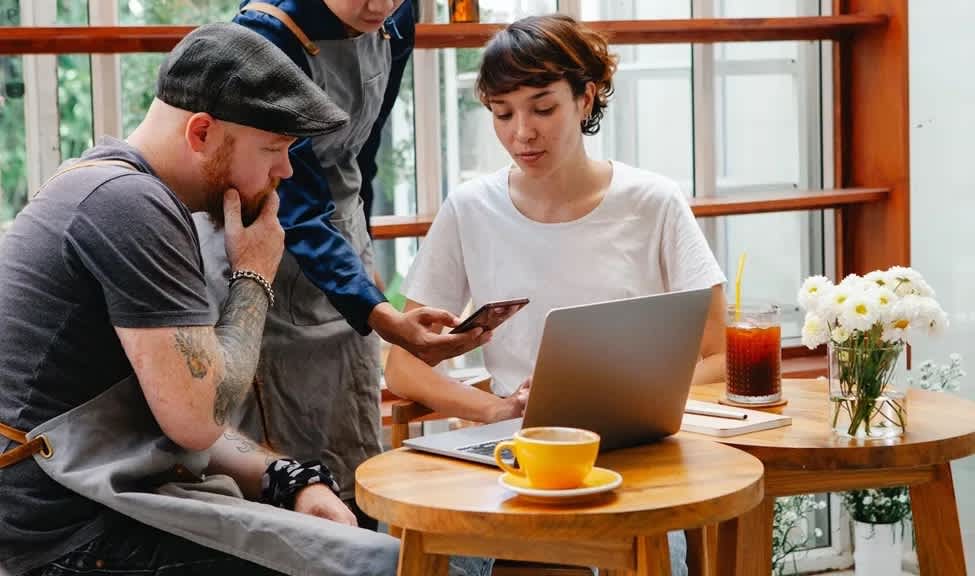 Group of small business owners working at a laptop in a cafe.