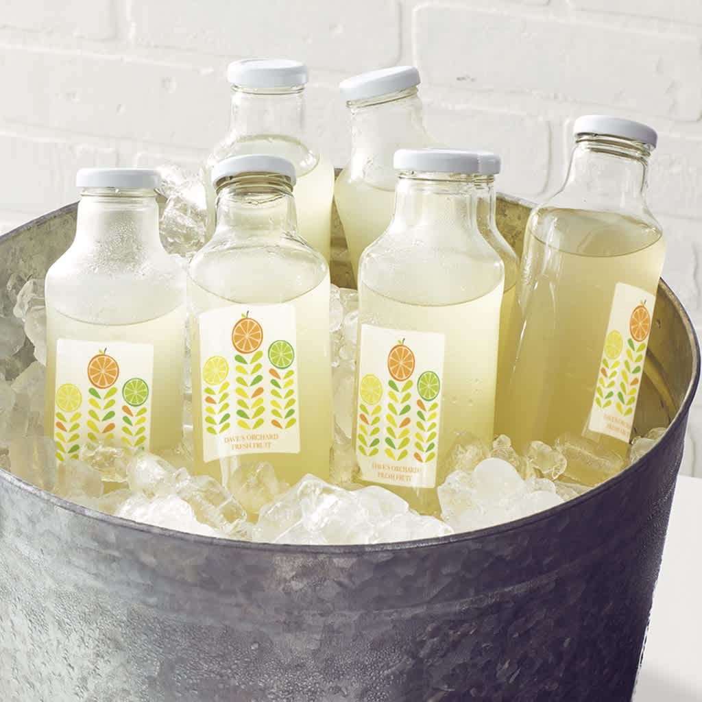 Galvanized tub of fresh lemonade in sustainable glass bottles features branded waterproof labels.