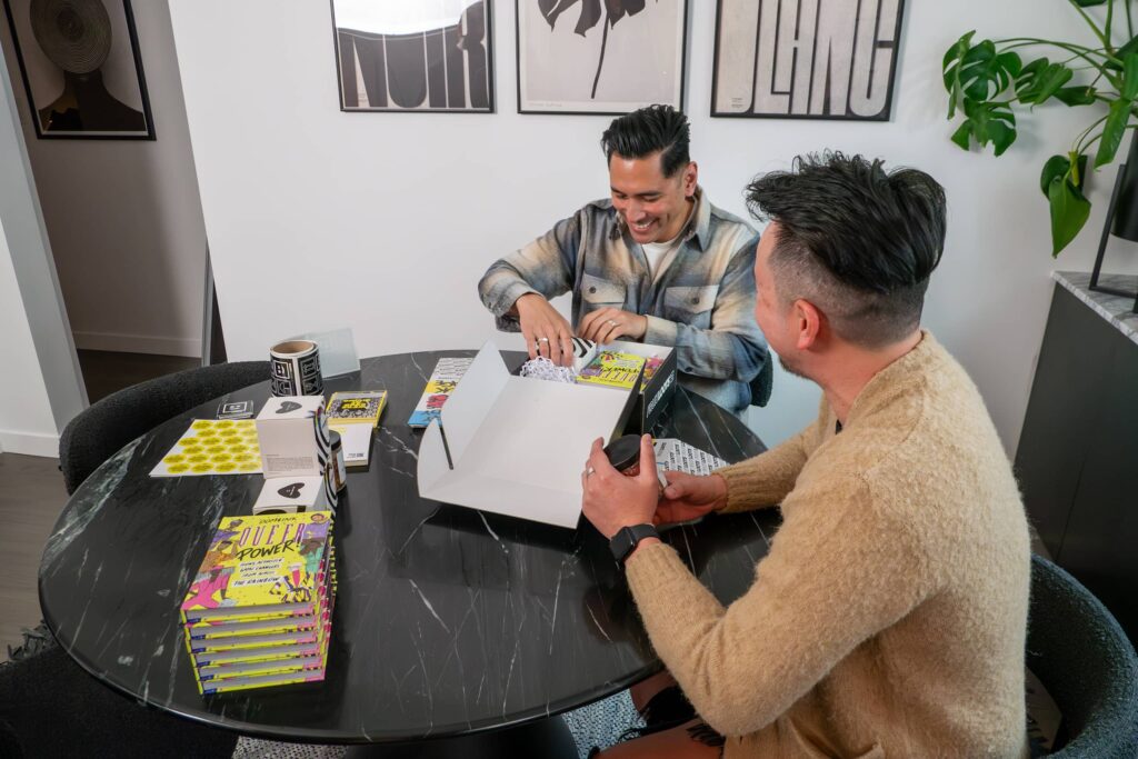 Two small business owners packing products into a mailer box at a table