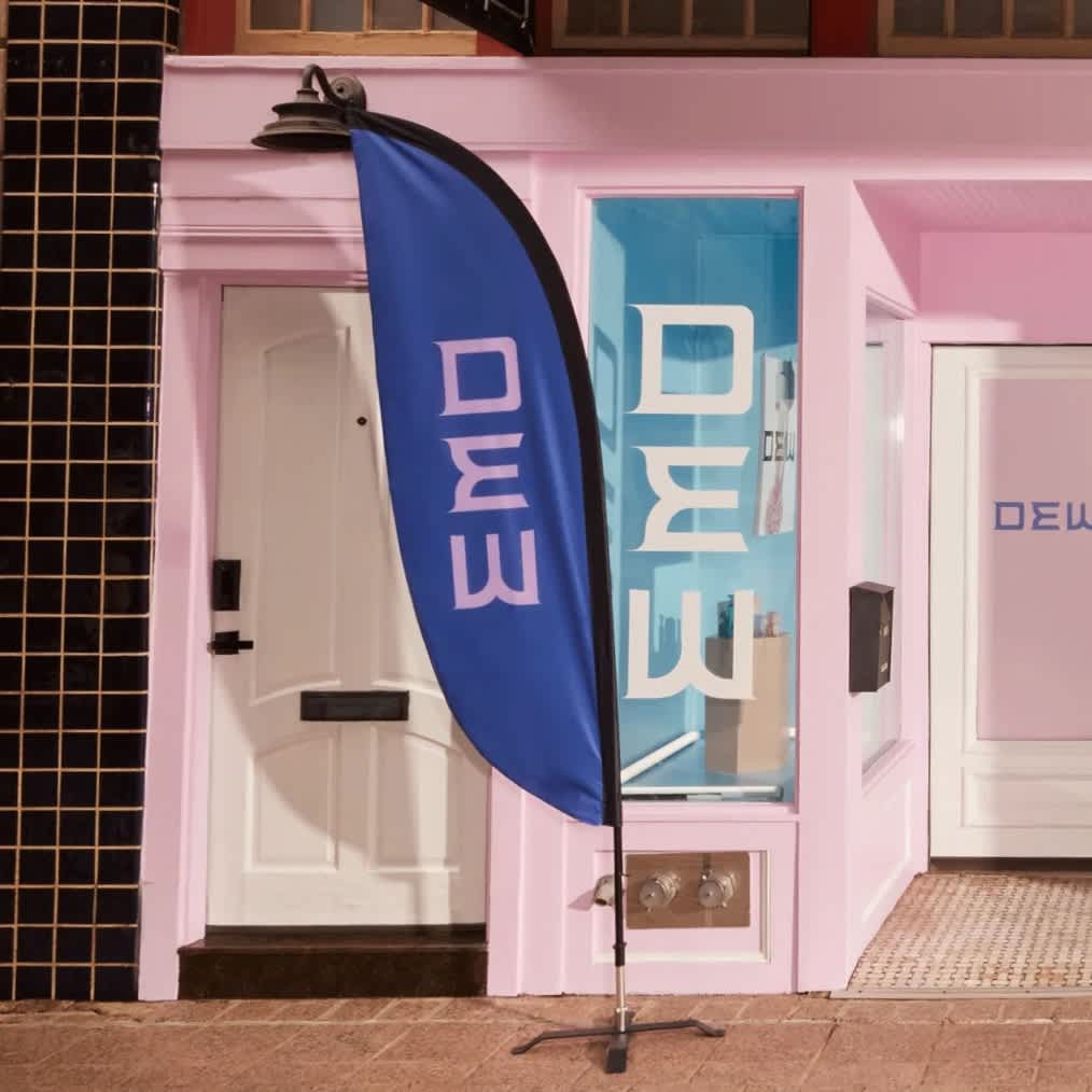 A blue and pink feather style banner beside a baby pink storefront for cosmetics brand, Dew.