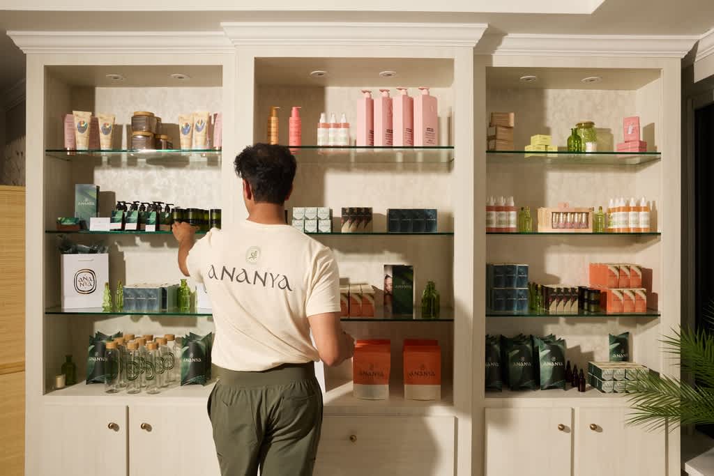Business owner with simple branded T-shirt checking spa retail products on shelves.