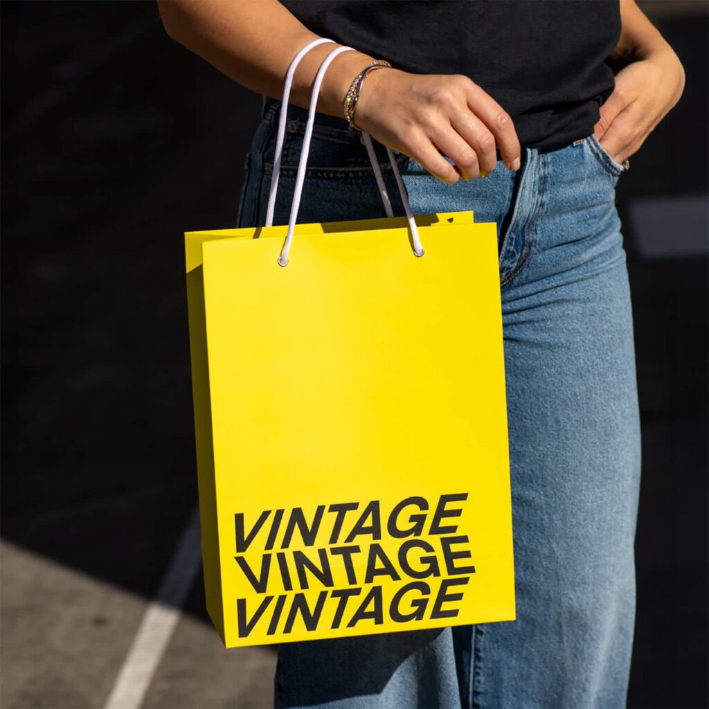 Minimalist packaging design featuring a bright yellow shopping bag with bold black typography repeated in a stacked layout.