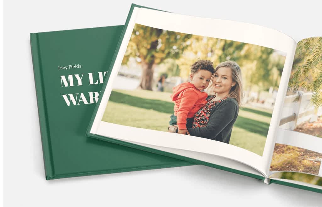 Simple green photo book with printed photo of mother holding child in the park.