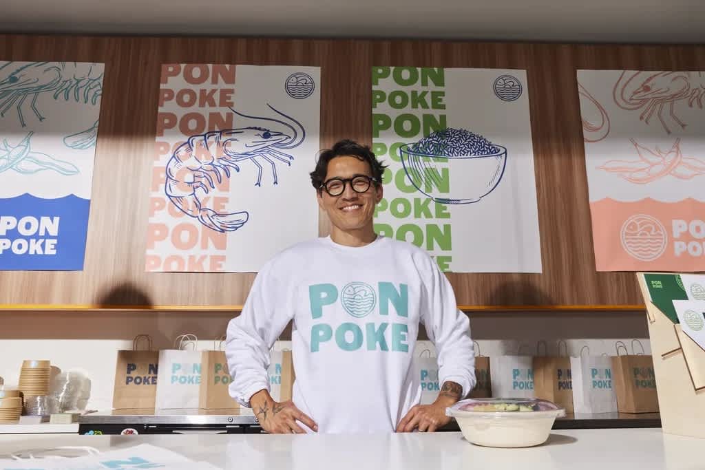 Person smiling at their salad counter; wearing branded merch