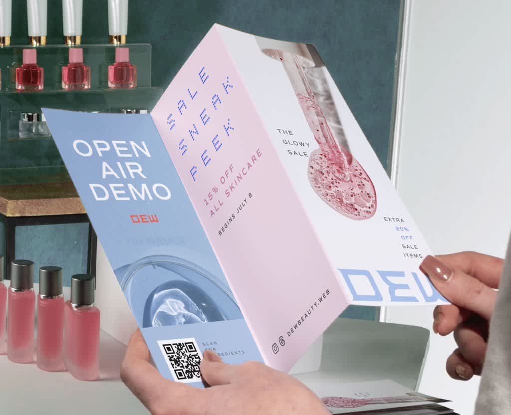 Someone holding a tri-fold promotional pamphlet featuring different typography styles, product photo and QR code.