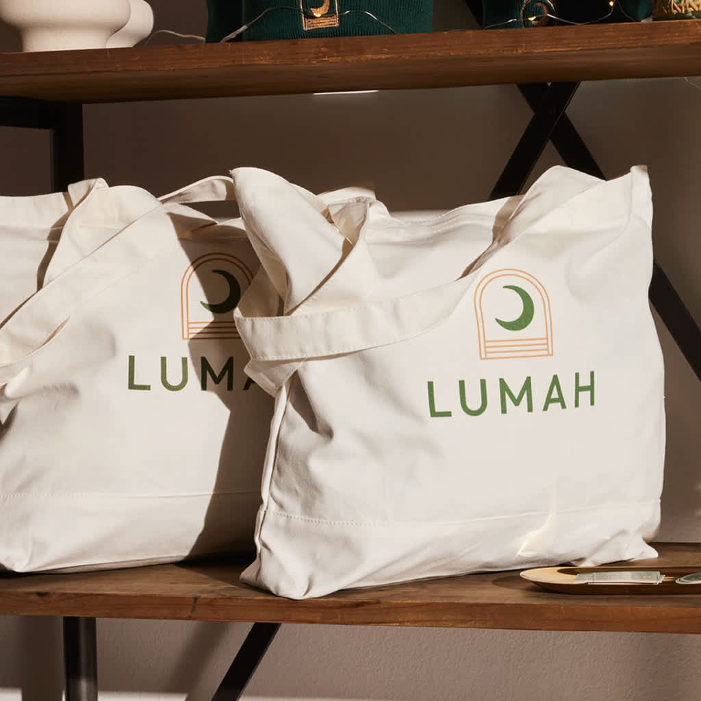 Two canvas tote bags with a logo and moon design printed on the front.