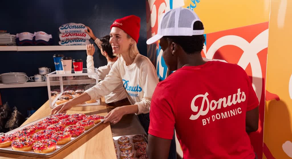Donut shop employees wearing branded apparel including custom caps and T-shirts.