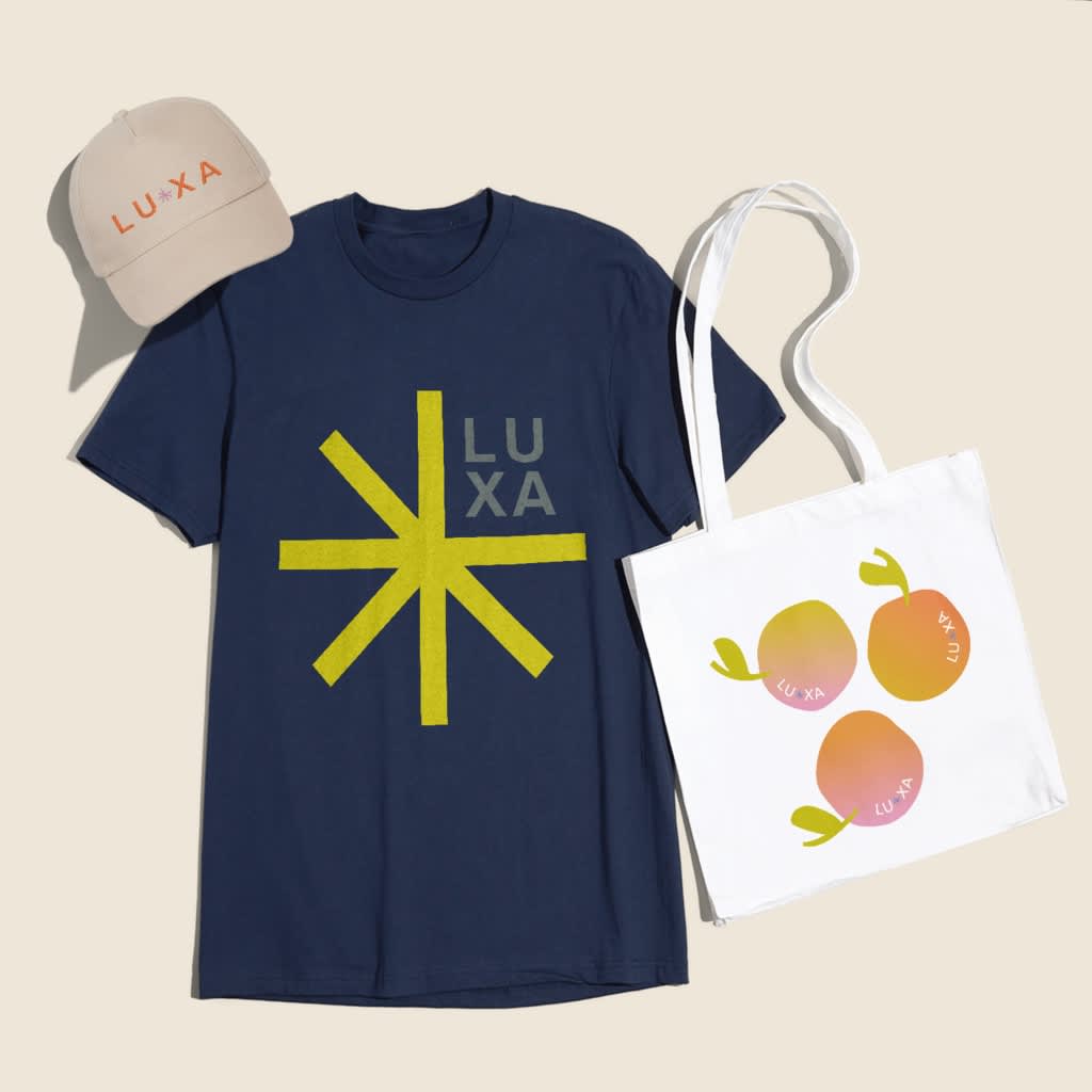 Navy blue T-shirt with large yellow asterisk-style graphic logo and similar branded logo on cap and tote bag.