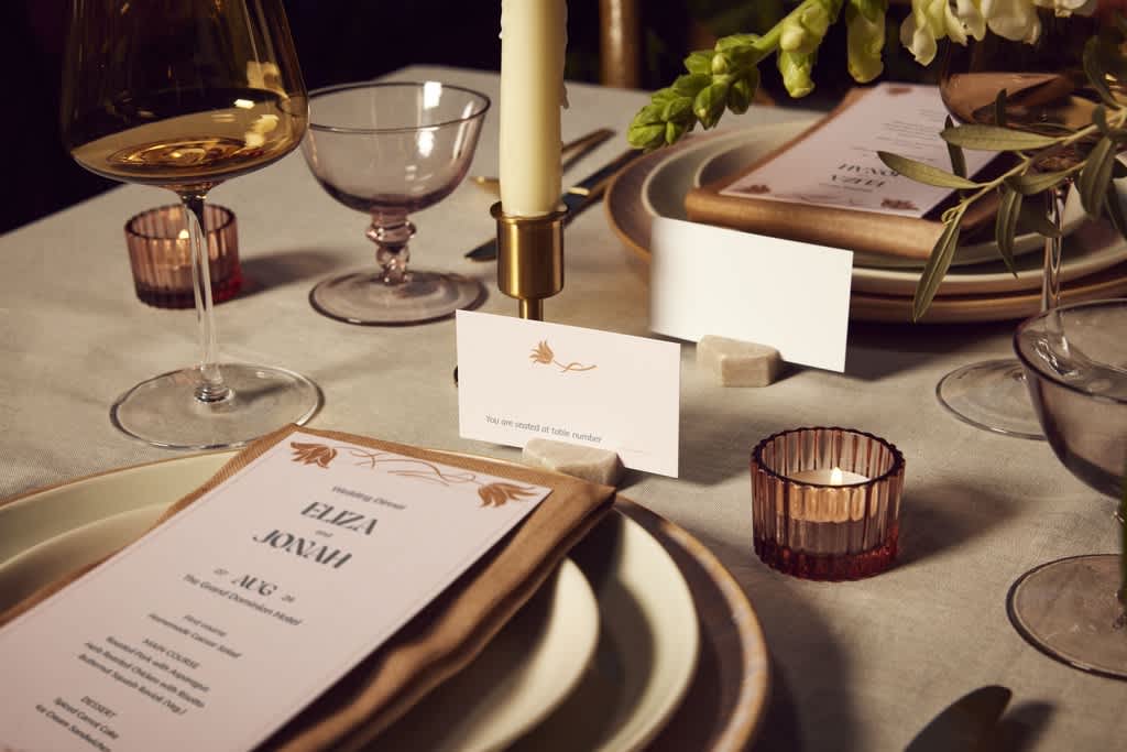 A a wedding table placement with candle, glasses and a plate with a personalized menu.