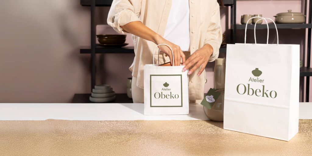 A white paper bag with black branding being packed with a product.