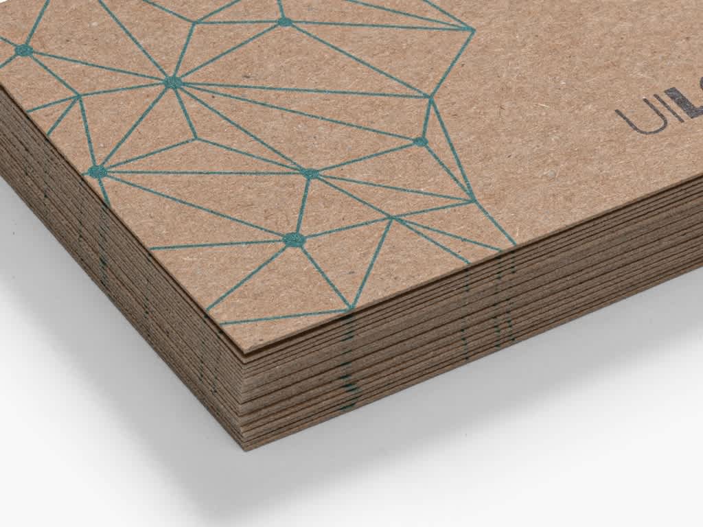 Close up of the corner of a stack of brown hemp stock business cards with fine blue graphic line drawing.