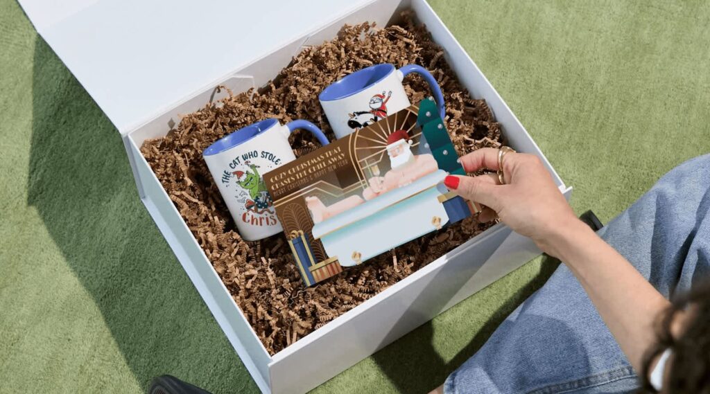 A business holiday card paired with a gift basket that includes two branded mugs.