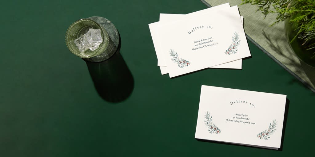 Matching Christmas card envelopes with printed recipient addresses on a dark green background.