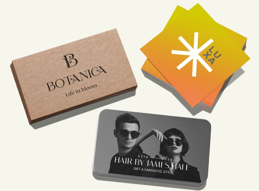 Selection of three business cards: a brown hemp stock with fine black font, bright yellow and orange square card with white chunky asterisk style logo and black and white photo card with image of two models and thin white font.