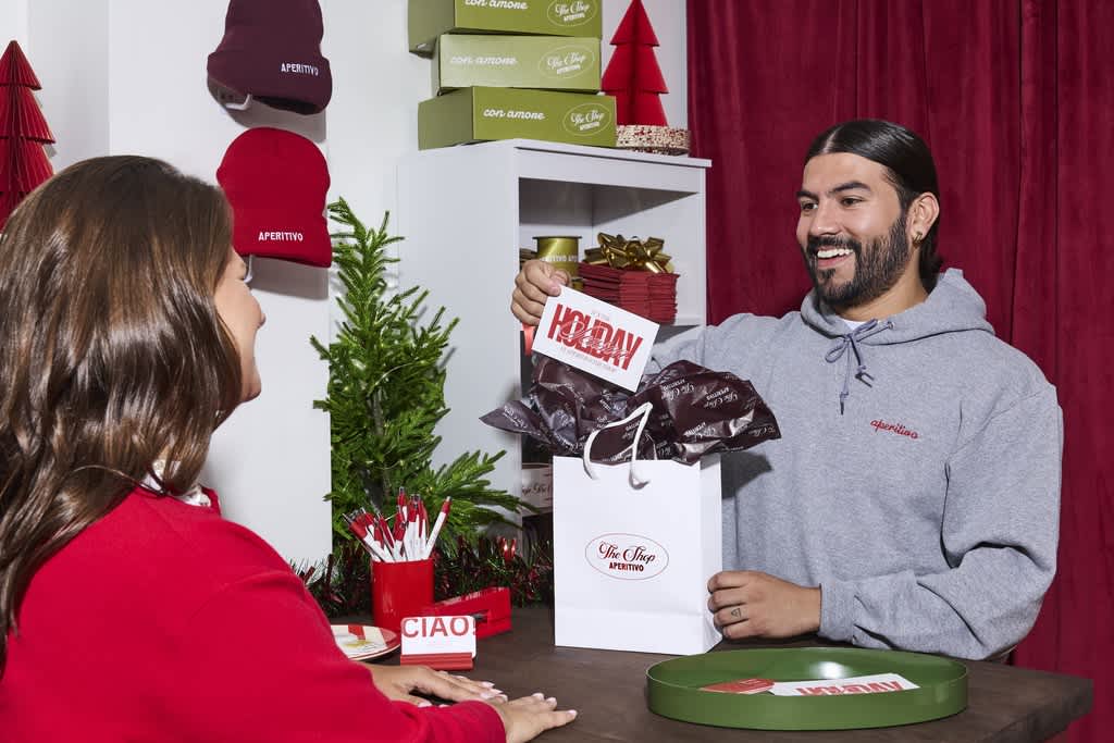 Business employee handing a custom Christmas card to a customer with a holiday gift bag.