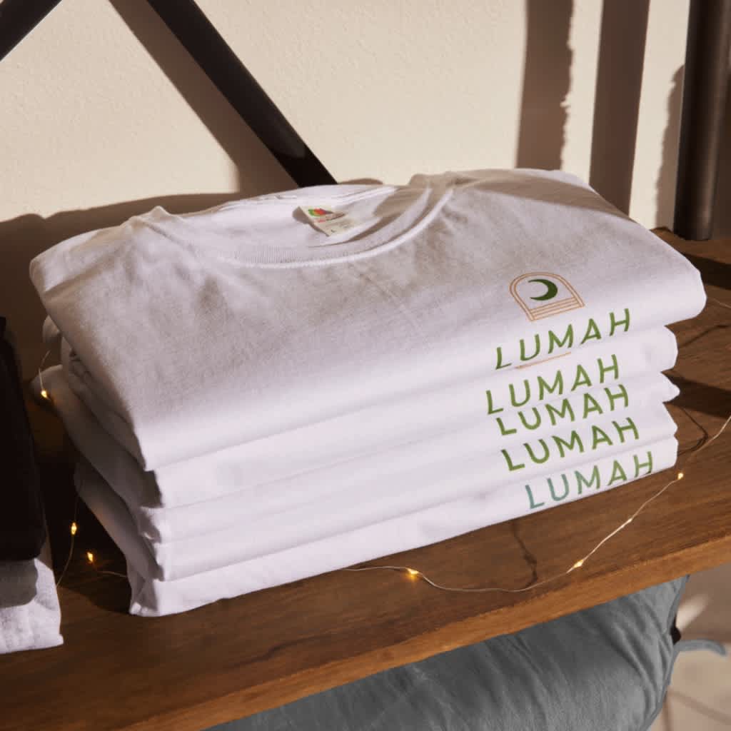 Stack of white folded custom T-shirts with a &ldquo;LUMAH&rdquo; printed business logo with crescent moon illustration.