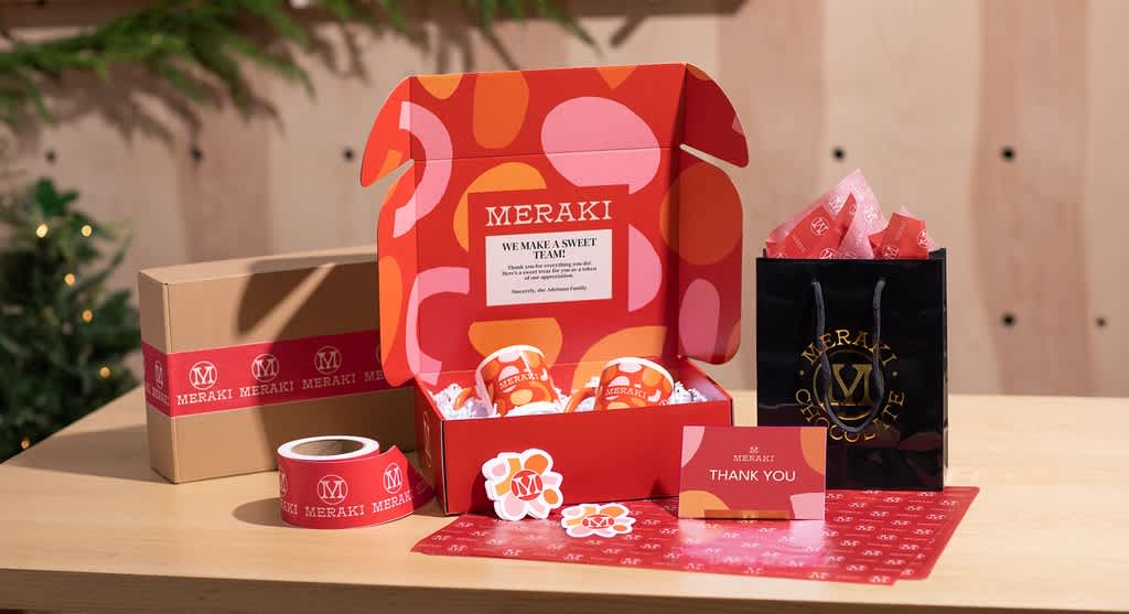 Example of Graphic Greetings style for holiday retail packaging, featuring geometric shapes as well as seasonal red complemented with on-brand pinks and orange rather than traditional greens and whites.