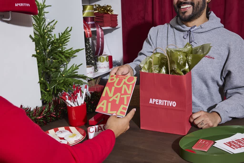A man handing over a branded booklet with a sold product in festive packaging.