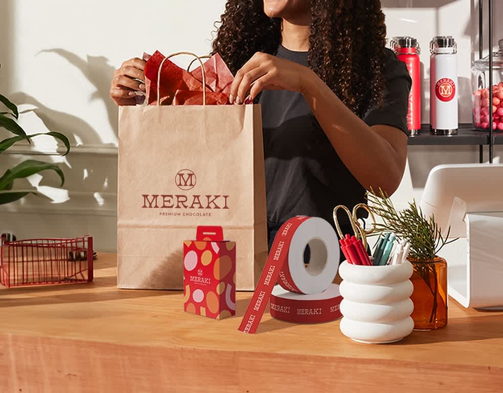 Woman handing nicely packed kraft bag with red and white decorations.
