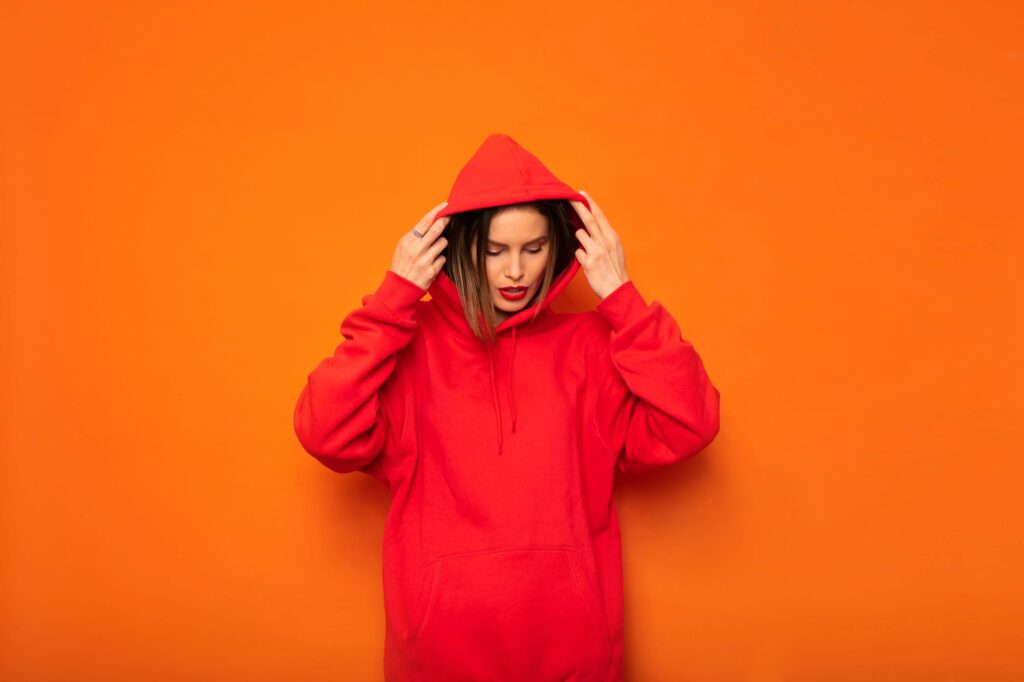 Person wearing a bright red hoodie against an orange background.